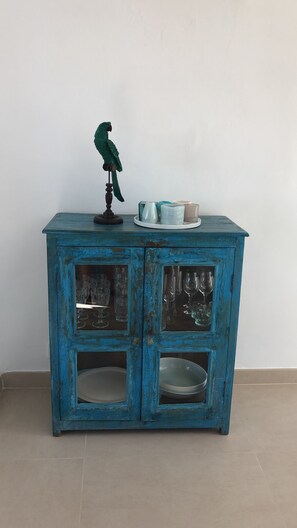 A teal-colored cabinet with glass doors, a small figurine on top, and a few decorative items on the top shelf. - House by the sea, private pool, sea view, roof terrace, air conditioning, WLAN, sep. Studio (Cala Serena)