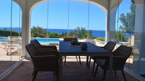 Une terrasse couverte avec vue sur l’océan, une piscine et du mobilier d’extérieur.