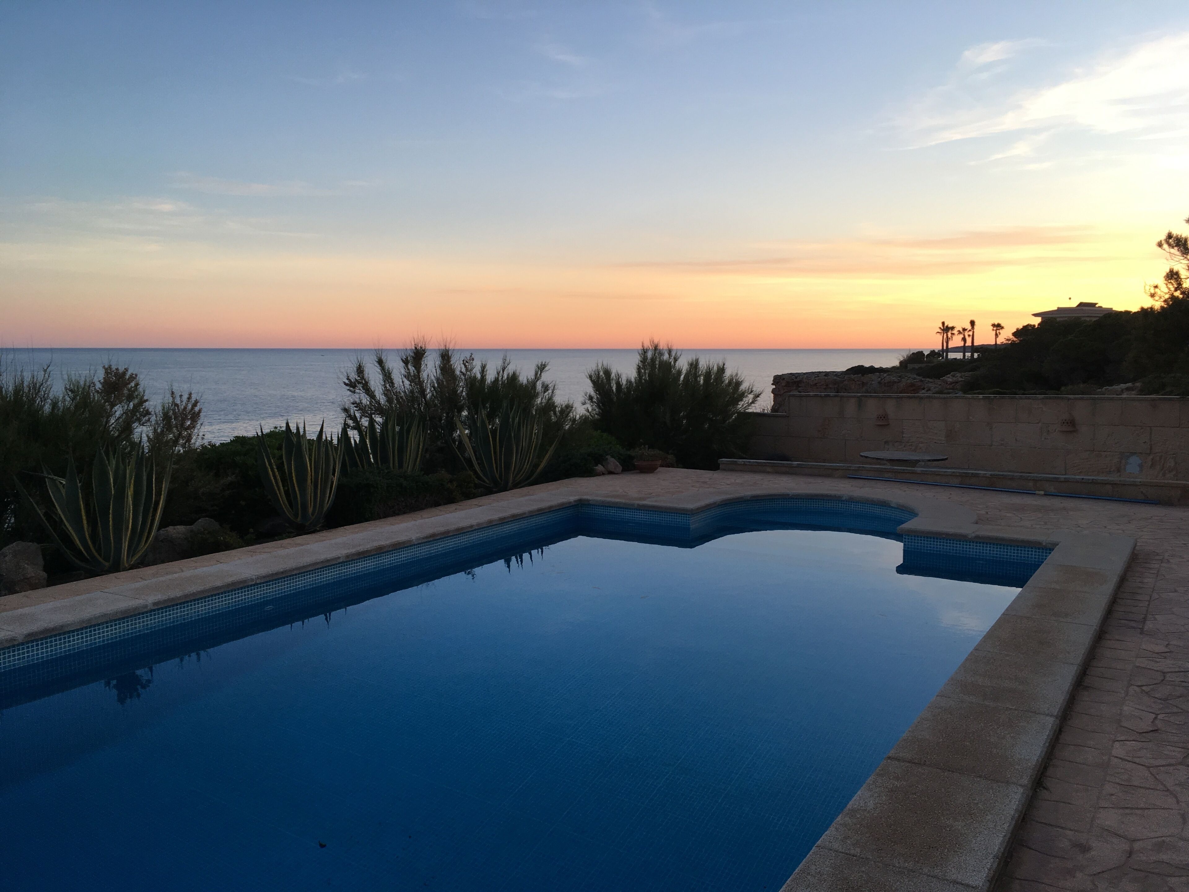 Une piscine avec vue sur l’océan au coucher du soleil.
