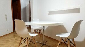 A small, modern dining area with a round table and four white chairs with wooden legs. - 2 room cozy Apartment - Sunny ground floor apartment with garden terrace in Forchheim (Forchheim)