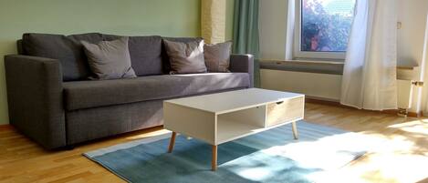 A modern living room with a grey sofa, a white coffee table, and a blue rug.