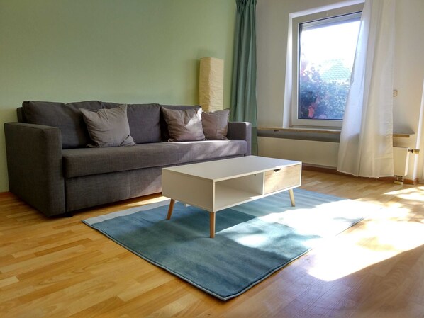 Ein modernes Wohnzimmer mit einem grauen Sofa, einem weißen Couchtisch und einem blauen Teppich.