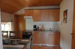 Kitchen area with stove, oven, coffee maker, sink, and window.