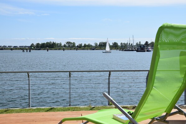 A waterfront view with a sailboat, a green chair, and a railing. - 1a location right on the water on the quay at Olpenitz! Schleiblick AND sea view! (Kappeln)