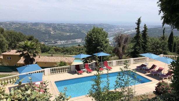A pool area with lounge chairs and umbrellas, surrounded by greenery and overlooking a scenic landscape. -  Holiday villa with communal pool, large terrace and magnificent sea views (Gattières)