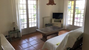 A room with a bed, a table, a TV on a stand, and large windows. -  Holiday villa with communal pool, large terrace and magnificent sea views (Gattières)