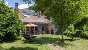 A house with a tiled roof, solar panels, a paved patio, and two rocking chairs.
