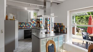 A modern kitchen with a central island, white cabinetry, and a colorful backsplash.