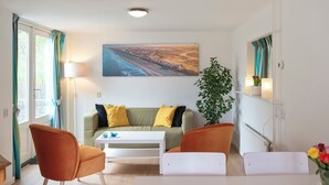 A modern living room with a sofa, two armchairs, a coffee table, and a large painting on the wall.