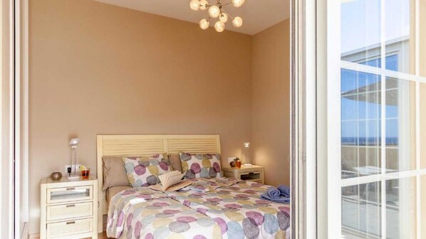 A bedroom with a bed, bedside tables, a nightstand, a window, and a chandelier. - Maxorata (Morro Jable)
