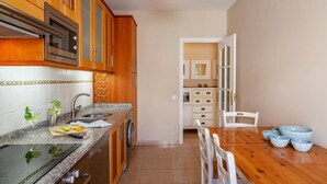 A kitchen with wooden cabinets, a granite countertop, a sink, and a dining area with a table and chairs.