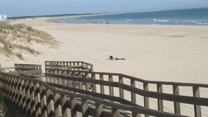 Una playa con un paseo marítimo de madera que lleva a la orilla.