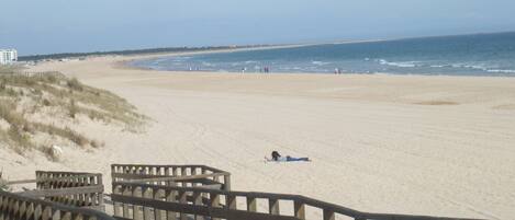 A beach with a wooden boardwalk leading to the shore.