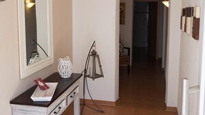 A hallway with a white console table, a mirror, a lantern, and a door leading to another room.