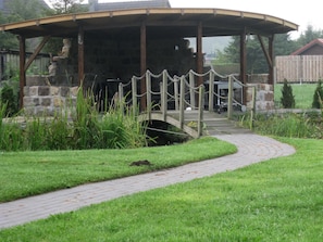 Un pavillon abrité, doté d’un mur en pierre et d’un pont en bois qui y mène.