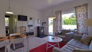 Een moderne woonkamer met een bank, stoelen, een eettafel en een televisie.