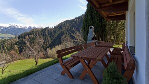 A wooden table and benches on a patio with a mountain view. - 4 to 12 people, ski vacation, hiking vacation, cultural vacation, quiet dreamlike location (Schlitters)