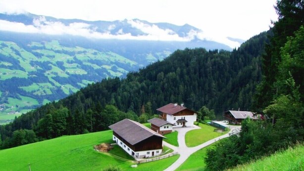 A rural landscape with a cluster of houses surrounded by lush green fields and a forested mountain backdrop. - 4 to 12 people, ski vacation, hiking vacation, cultural vacation, quiet dreamlike location (Schlitters)