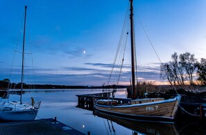 A calm marina with boats docked, a clear sky, and a visible moon. - "Söt`Hafenhus" at the idyllic, small harbor, with a wide view of Bodden meadows (Pruchten)