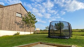 A backyard with a sandbox, a trampoline, and a wooden barn. - Cozy vacation apartment in the countryside - ideal for switching off & relaxing (Niederbobritzsch)