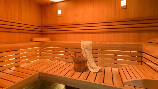 Un sauna avec des bancs en bois et un seau en bois.