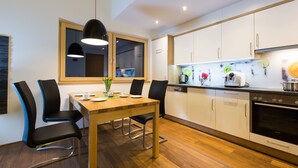 Une cuisine moderne avec des meubles blancs, une table à manger en bois et des chaises noires.