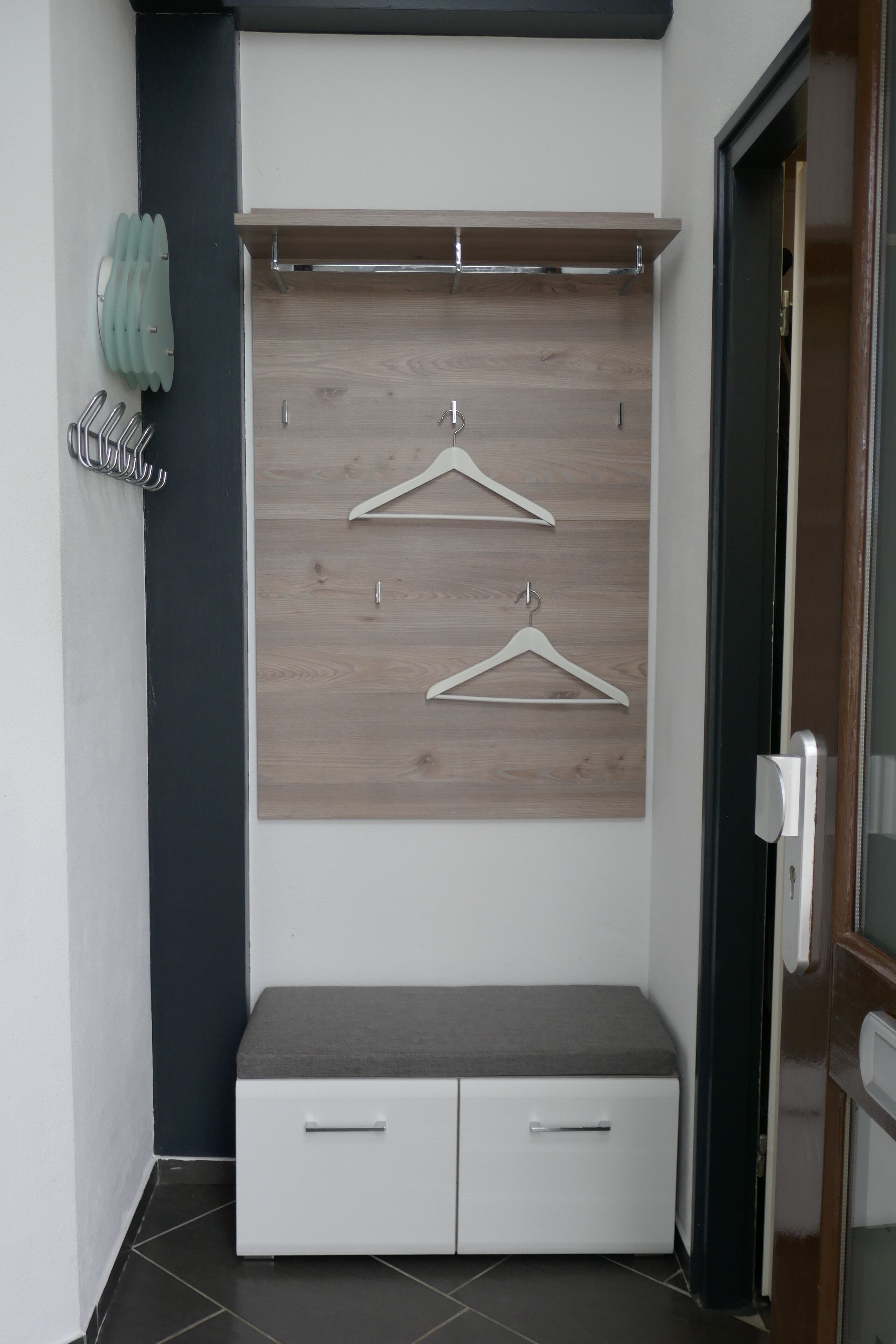 A modern room with a built-in bench, a coat rack, and a door.