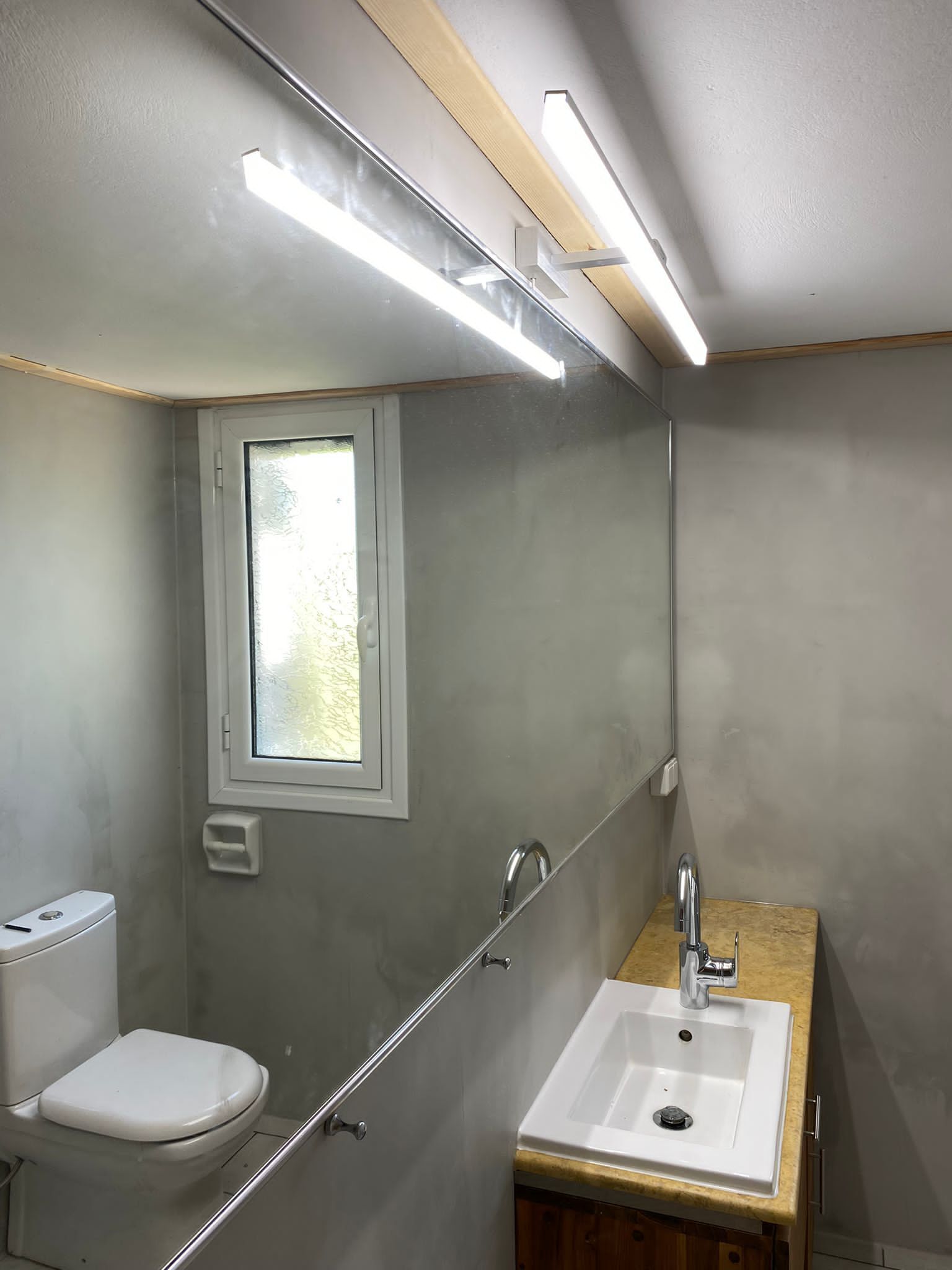 A compact bathroom with a toilet, sink, and window.