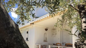 A white building with a balcony, a hanging decoration, and a tree in the foreground. - Top holiday home private pool by the sea with private garden for single use (Koroni/Harakopio)