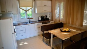 A compact kitchen with white cabinets, a wooden table, and a bench. - Top holiday home private pool by the sea with private garden for single use (Koroni/Harakopio)