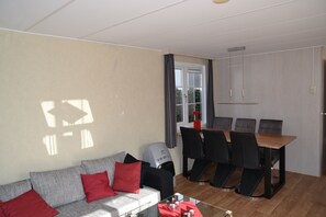 Ett vardagsrum med en soffa, ett soffbord och en matplats med ett bord och stolar.