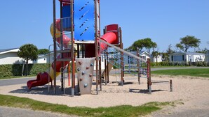 Ein Spielplatz mit einer roten Rutsche, einer Kletterwand und einer roten Spiralrutsche.