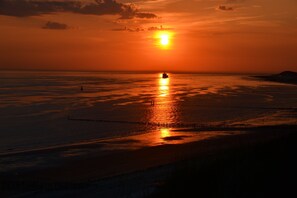 Een zonsondergang boven een rustige zee, met een boot in de verte.