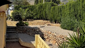 A courtyard with a stone wall, a staircase, and a view of mountains.