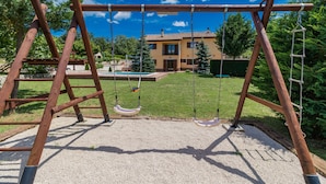 A wooden swing set in a backyard with a house and pool in the background. - New luxurious and modern Villa, 5 minutes from the nearest beach (Krsan)