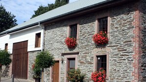 Un edificio de piedra con puertas y ventanas de madera, algunas adornadas con flores rojas.