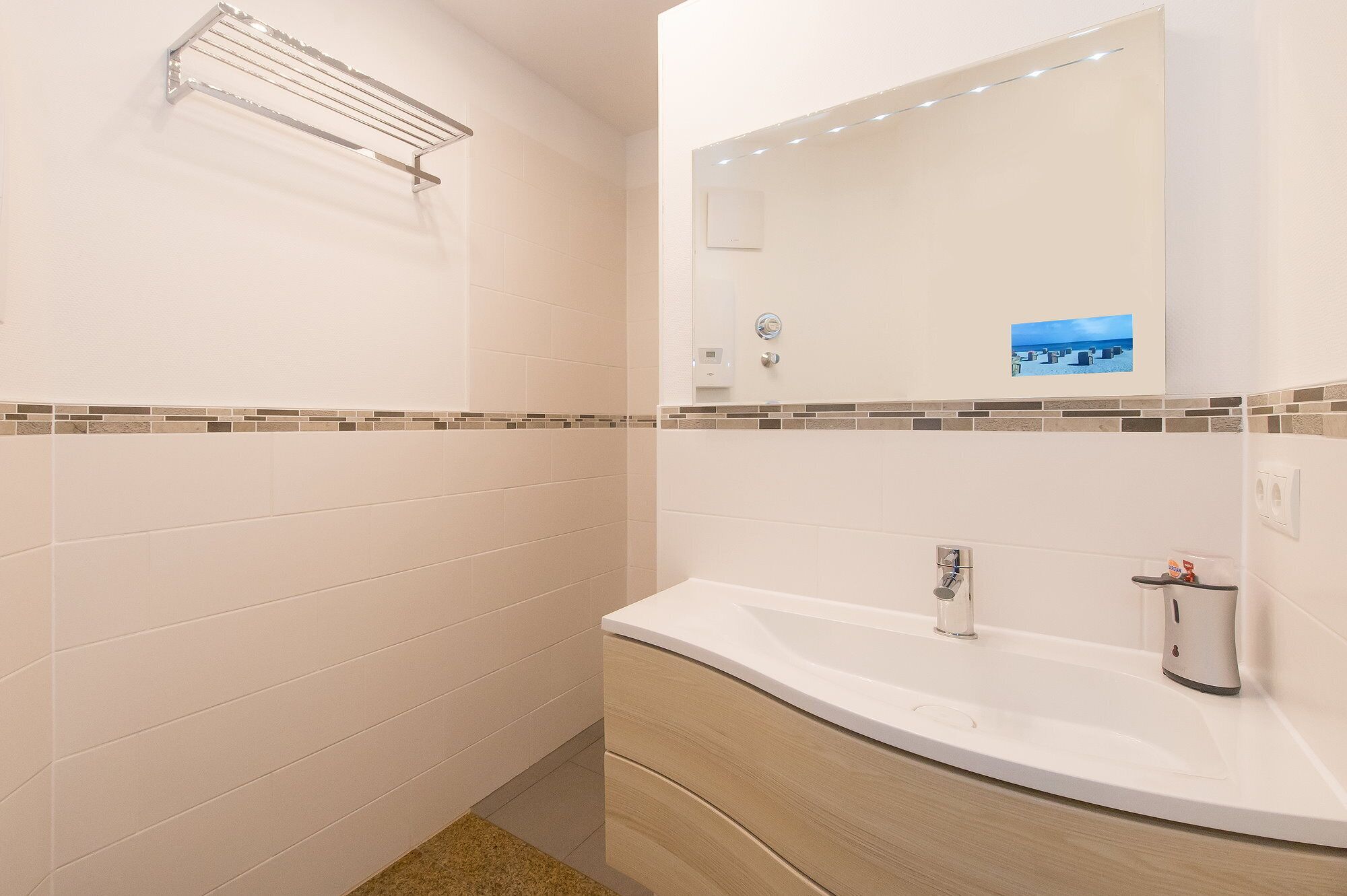 Une salle de bain avec un lavabo blanc, un miroir et un espace douche.