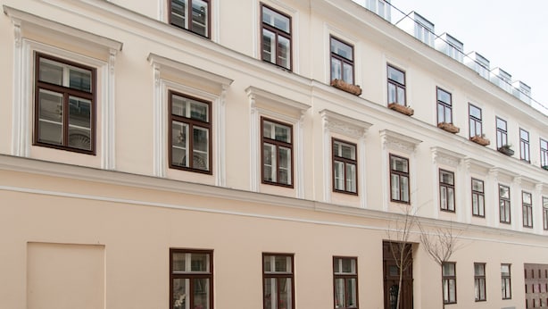 Um edifício com vários andares, janelas uniformemente distribuídas e fachada simétrica.