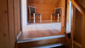 Un escalier en bois mène à une pièce où se trouvent deux chaises et une fenêtre.
