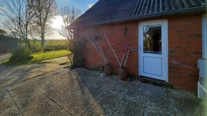 Une maison en briques avec une porte blanche et un toit en métal.