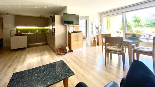 En moderne lejlighed med et køkken, spiseområde og en stor skydedør til en balkon.