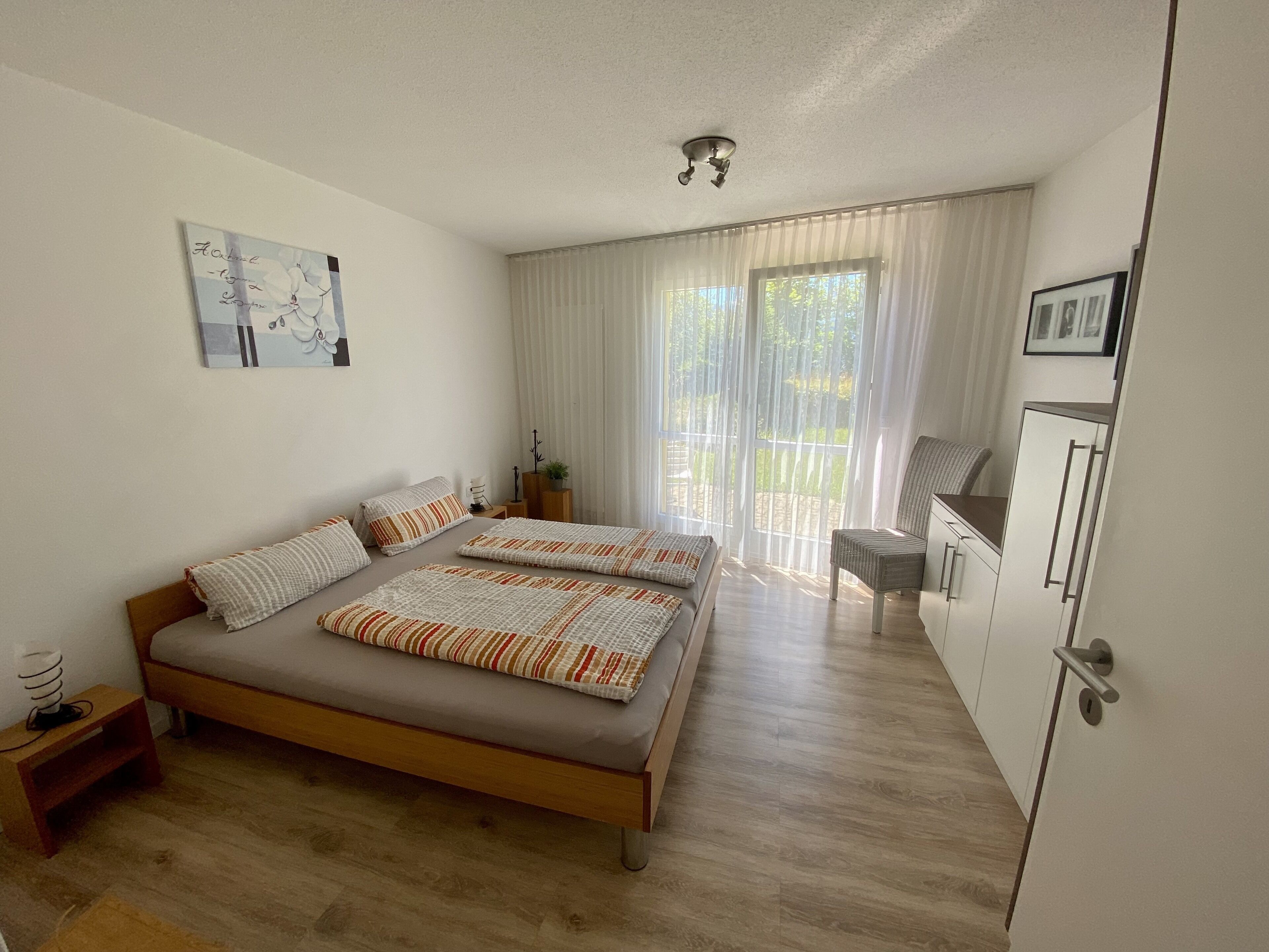 Quarto com uma cama de casal, uma escrivaninha e uma cadeira.