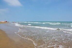 Une plage avec une eau d’un bleu limpide et un rivage sablonneux.
