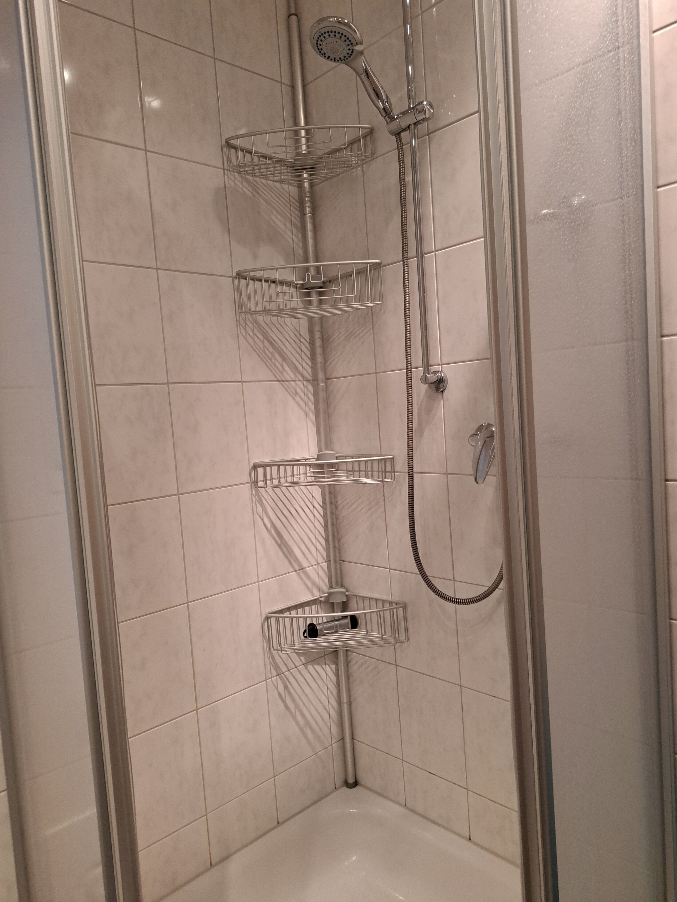 A shower with a handheld showerhead and a handheld shower attachment.