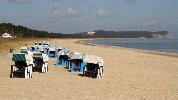 A beach with rows of beach huts, a sandy beach, and a calm sea. - Exclusive apartment with sea views, south-facing terrace, garden u. parking spot (Groß Zicker)