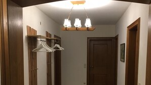 A hallway with a wooden door at the end, a hanging coat rack, and a patterned rug on the floor. - Panorama-FeWo**** BEI WINTERBERG, 2 -10 pers., box-spring beds, WIFI / WLAN  (Schmallenberg)