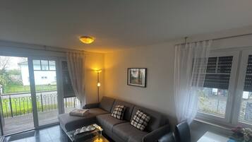 Ein modernes Wohnzimmer mit einer Couch, einem Couchtisch und einer Essecke mit Tisch und Stühlen.