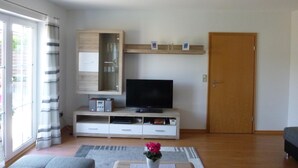 A modern living room with a TV, wooden cabinet, and a door. - **** late harvest apartment (Leiwen)