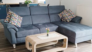 A modern living room with a sectional sofa, a wooden coffee table, and a kitchen in the background. - **** late harvest apartment (Leiwen)