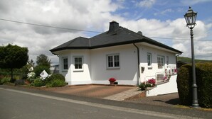 A white house with a black roof, a brick driveway, and a street lamp. - **** late harvest apartment (Leiwen)